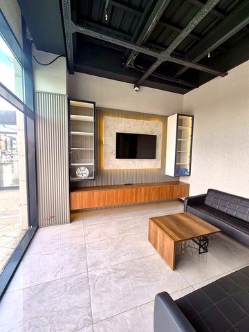 Işıklı mermer TV duvarı, çıtalı paneller, ahşap konsol ve deri kanepeli salon