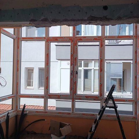 Yeni takılmış koruma bantlı PVC pencereler ve balkon kapaması
