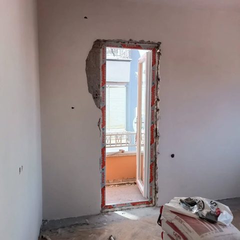 Söküm aşaması: balkon kapısı açılmış duvar, sıva hazırlığı ve çimento torbası